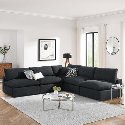 Black boucle fabric sectional with chaise; modern living room featuring glass coffee table & round side table.