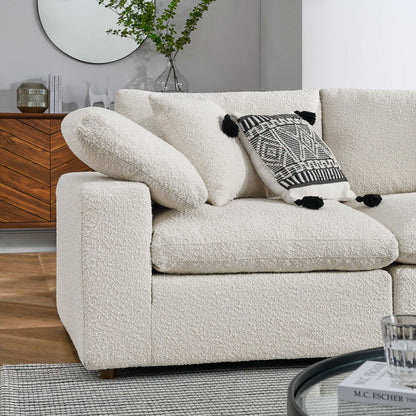 Ivory boucle sectional sofa with rounded arms and plush cushions, featuring a black & white geometric throw pillow.