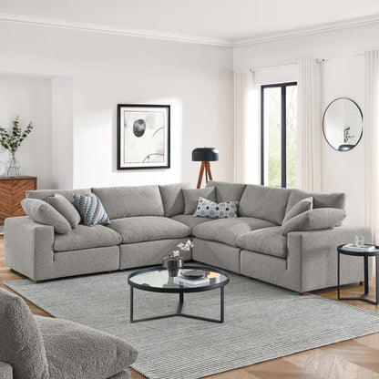 Light gray boucle sectional sofa (L-shaped) with mixed cushions, round glass-top coffee table, and gray rug in a modern living room.