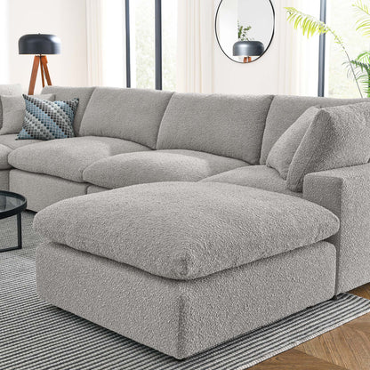 Light gray boucle sectional sofa with oversized matching ottoman in a modern living room.