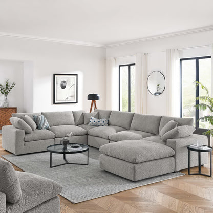 Light gray fabric modular sectional with chaise, round glass coffee table, gray rug, white curtains in modern living room.