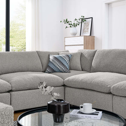 L-shaped light gray textured fabric sectional sofa with a blue geometric pillow, round glass coffee table in a modern living room.