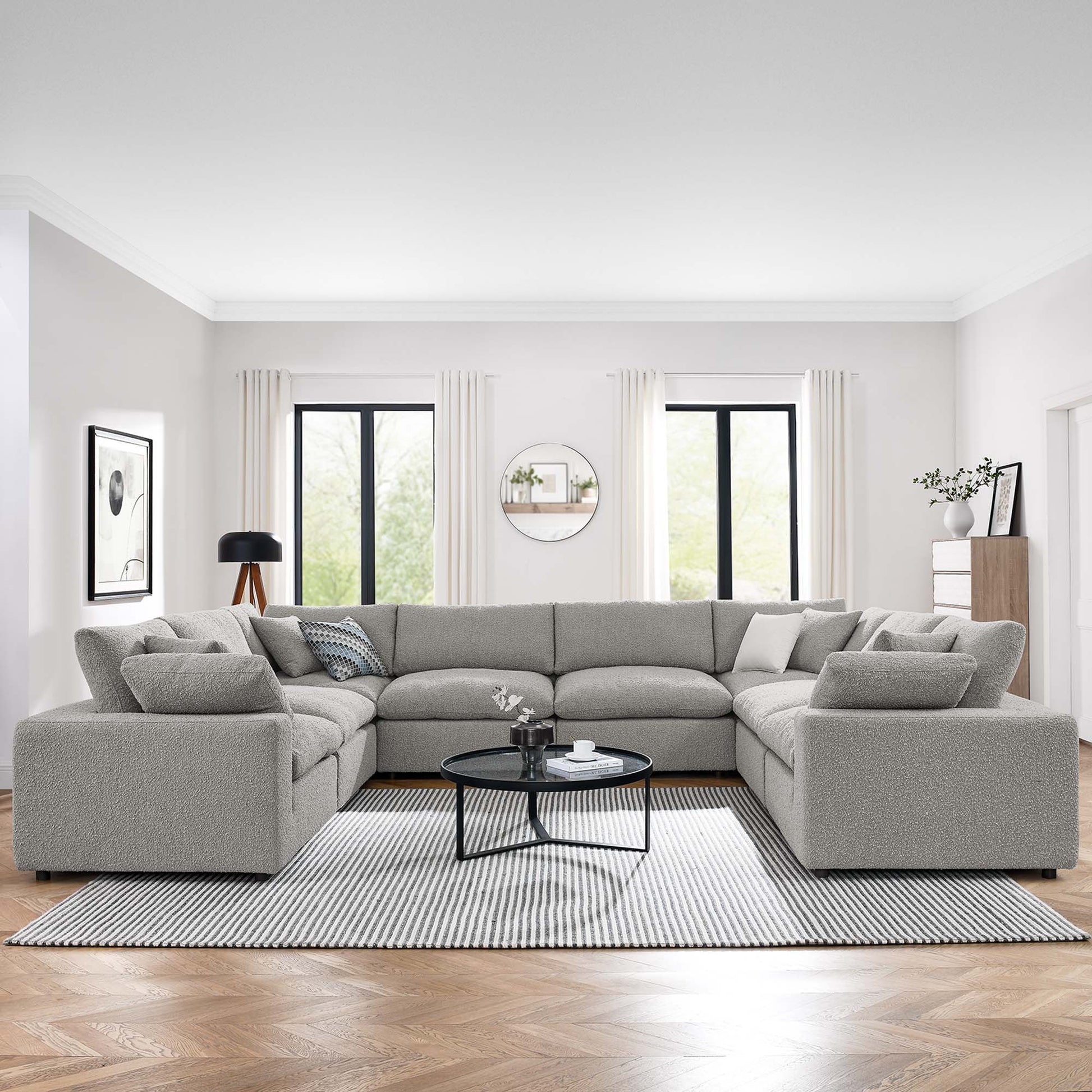 Light gray L-shaped fabric sectional sofa in a modern living room with a round black coffee table and striped rug.