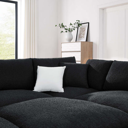 Charcoal black fabric L-shaped sectional sofa with a white pillow in a bright modern living room light wood dresser and vase.