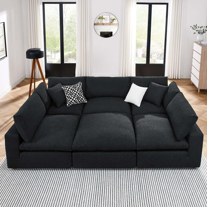 Dark charcoal fabric sectional sofa with plush cushions in a modern living room; includes patterned and white throw pillows.