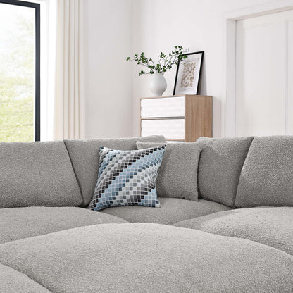 Light gray modular sectional sofa with boucle fabric and a blue-gray geometric pillow; white wood console with a vase and framed art.