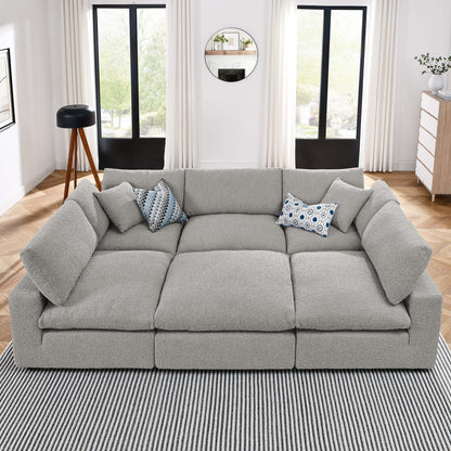 Gray fabric modular sectional sofa with deep cushions and blue patterned throw pillows in a bright living room.