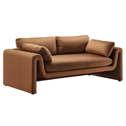 Brown velvet sofa with sculpted curved arms, deep seat cushions, and matching throw bolsters; modern lounge.