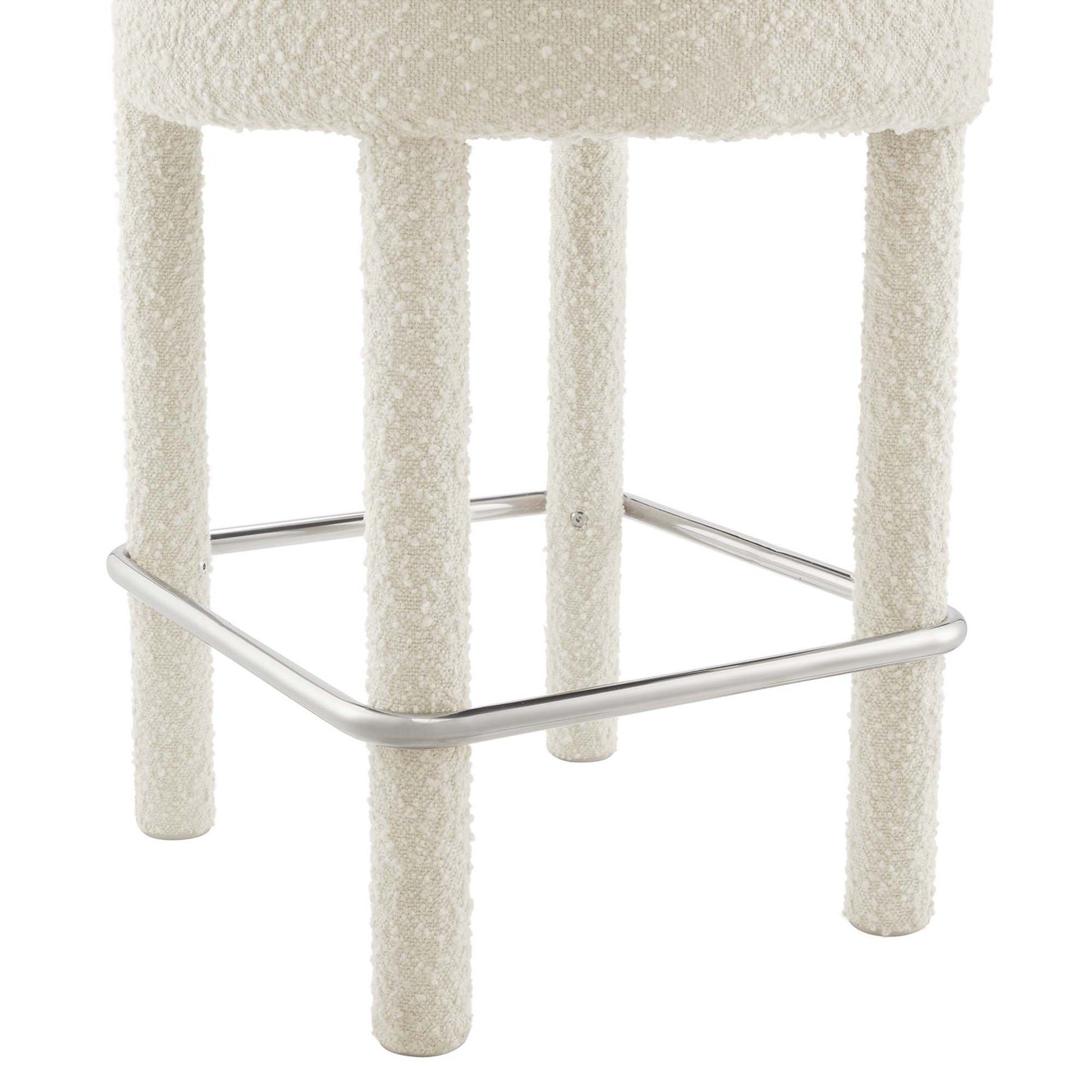 Silver boucle upholstered counter stool with four textured legs and chrome footrest.