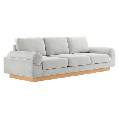 Light gray fabric sofa with three seat cushions, rounded rolled arms, and a natural wood platform base.