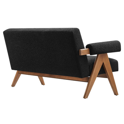 Mid-century black boucle loveseat with a wooden frame, angled legs & low-profile armrests.