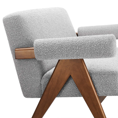 Mid-century style loveseat in light gray boucle fabric with cylindrical padded armrests and warm angled wooden legs.