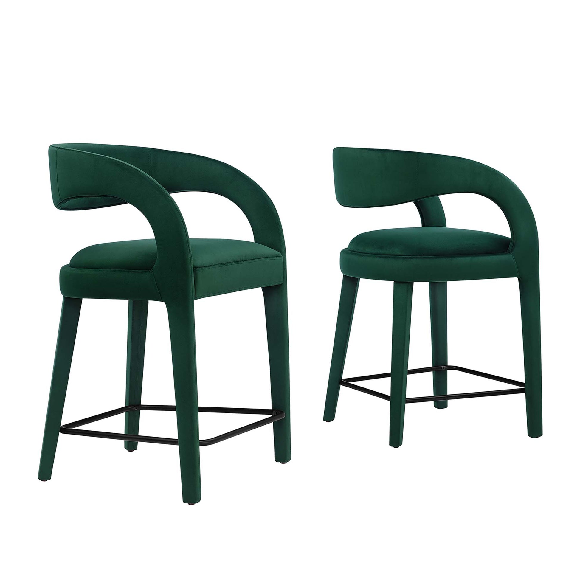 Pair of emerald green velvet counter stools with curved back arms and black metal footrests.