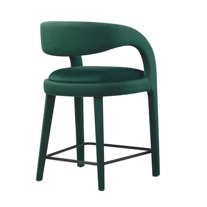 Emerald-green velvet counter stools with curved backs, round cushioned seats, and black metal footrests.