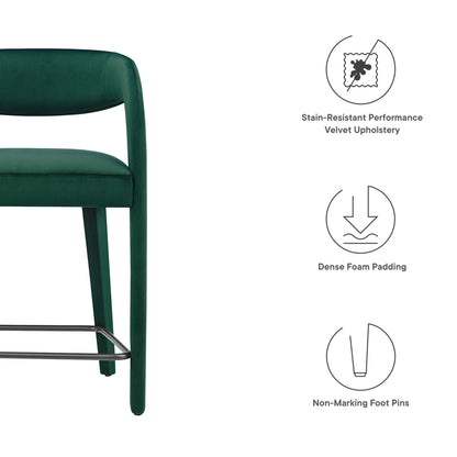 Emerald green velvet upholstered curved-back counter stool with chrome footrest and dense foam padding