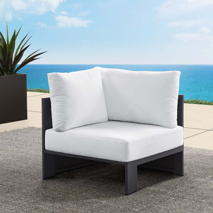 Outdoor modular corner chair with white cushions and a powder-coated aluminum frame on a seaside patio.