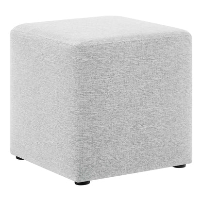 Light gray fabric cube ottoman with rounded edges and small black feet, modern living room pouf.