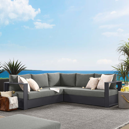 L-shaped gray outdoor sectional with dark frame, light gray cushions and beige pillows on a seaside patio.