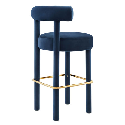 Navy blue velvet bar stool with round cushioned seat, tubular backrest and gold metal footrest.