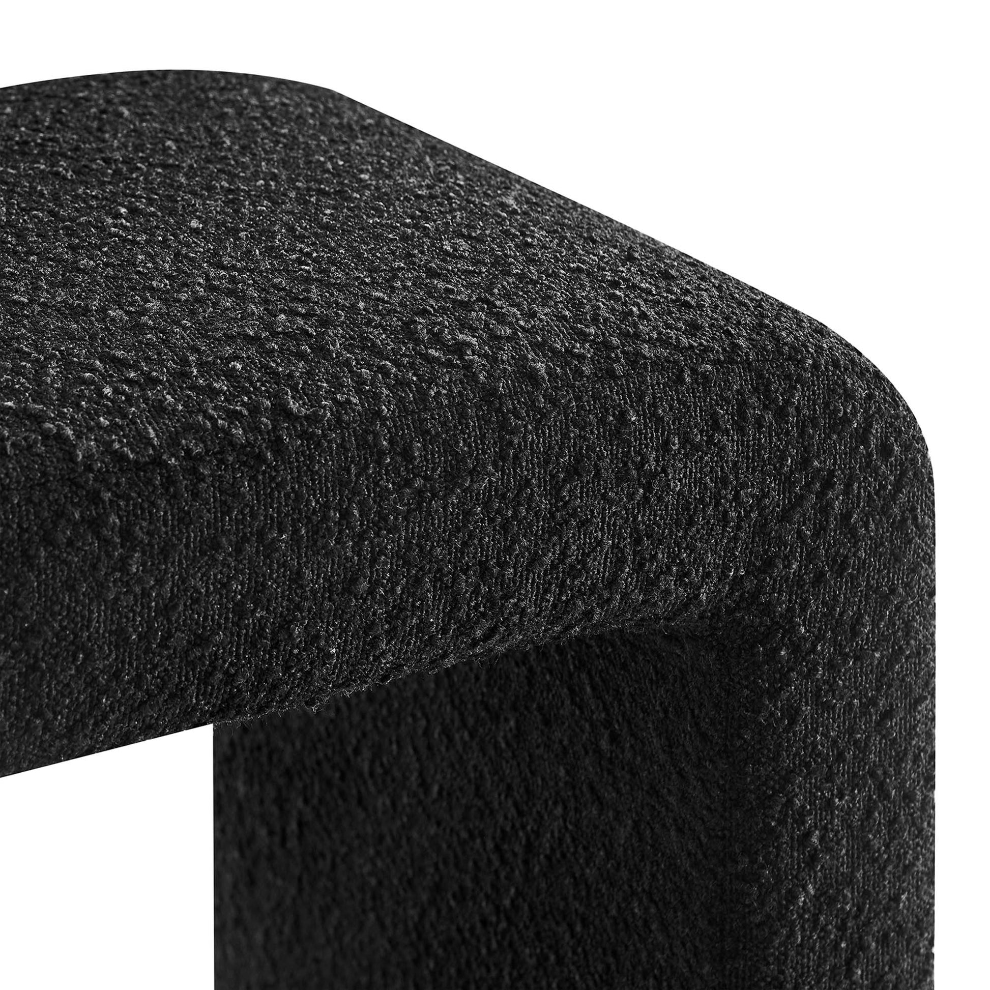 Black textured fabric upholstery on a rounded stool, close-up.