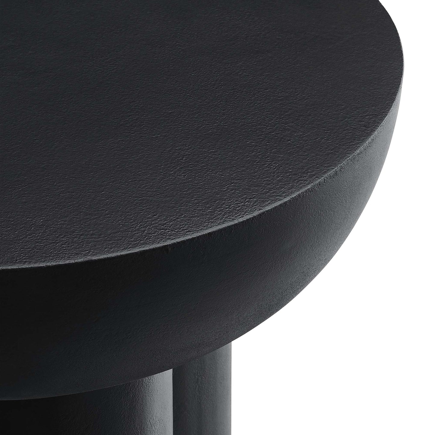 Black round concrete side table with matte finish and partial leg.