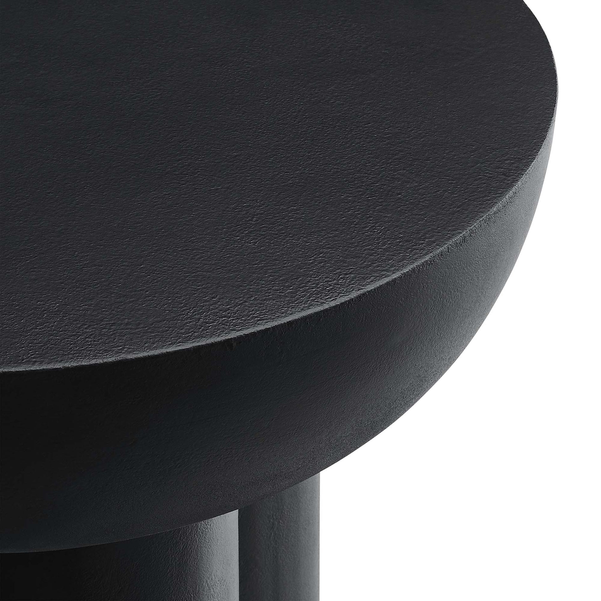 Black round concrete side table with matte finish and partial leg.