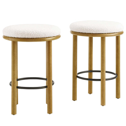 Two round counter stools with white boucle fabric seats, light oak legs & black metal footrests; modern rustic style.