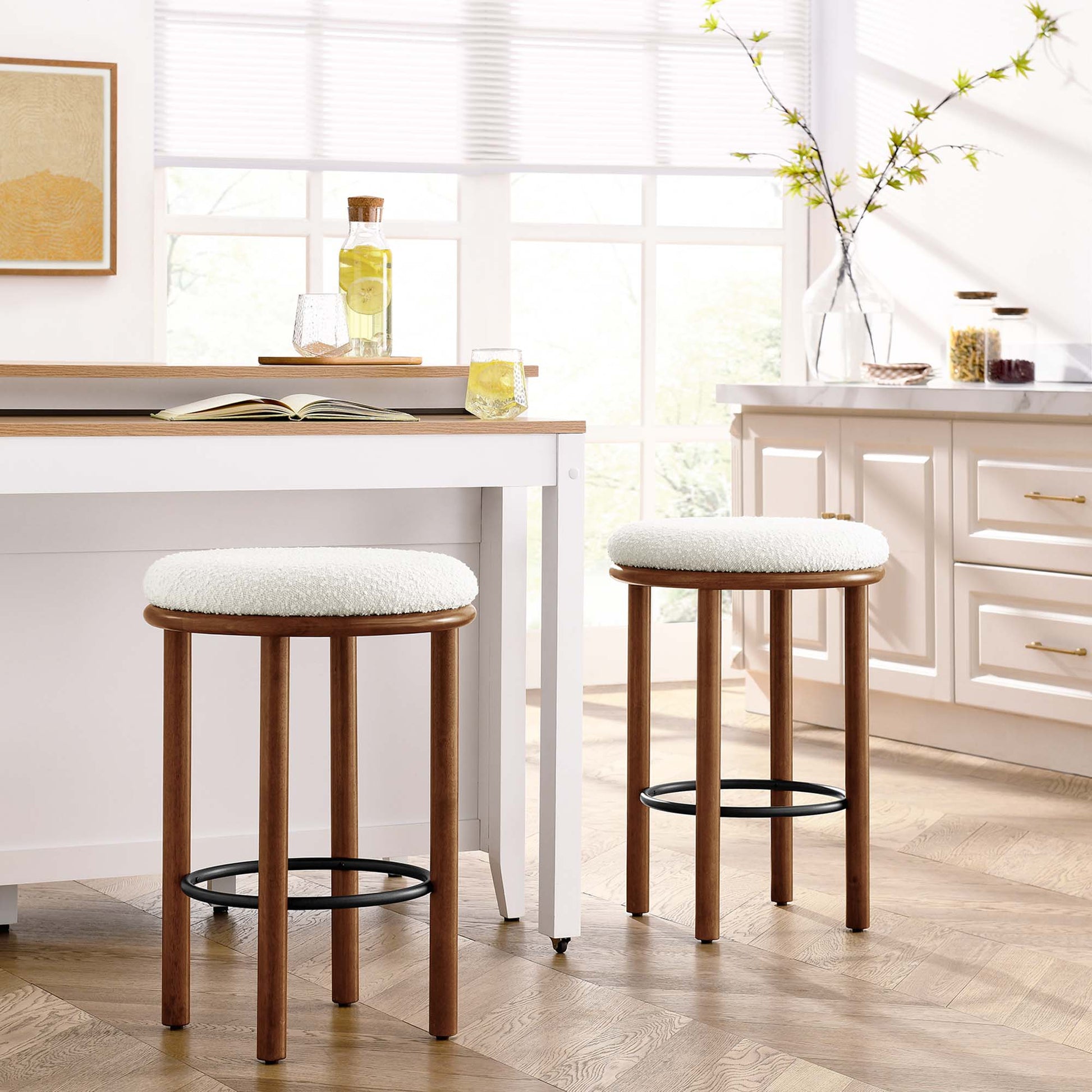 Pair of walnut-finish counter stools with ivory boucle seats and black metal footrings for kitchen island.
