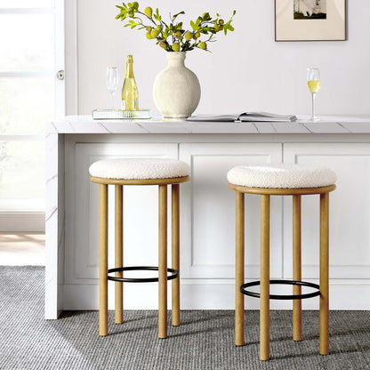 Two ivory-cushioned oak bar stools with black footrests at a white kitchen island, with vase and champagne.