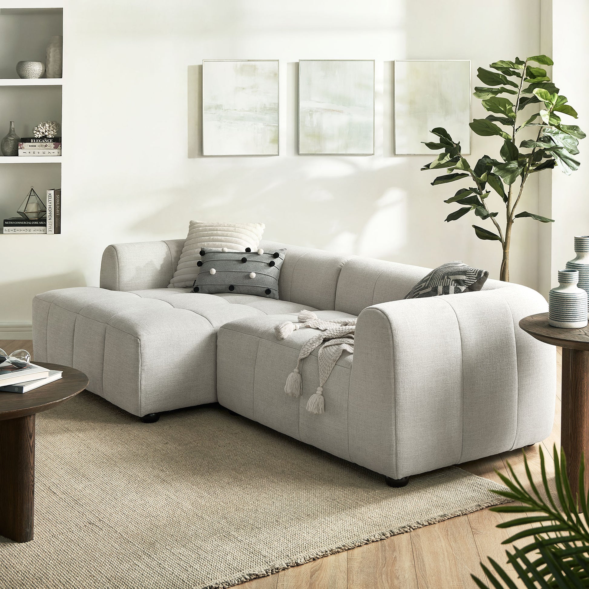 White fabric left-facing modular sofa with chaise in a bright living room.
