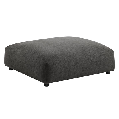 Charcoal gray fabric ottoman with rounded edges, low profile, rectangular shape and short black feet.