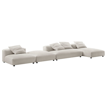Gray fabric sectional sofa with modular 4-piece layout and ottoman; low-profile design with cushions & pillows on connected sections.