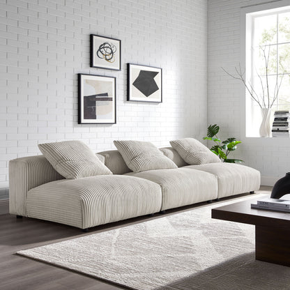 Brown corduroy 3-piece modular sofa in a white brick-walled living room with abstract wall art, gray rug, and a wooden coffee table.