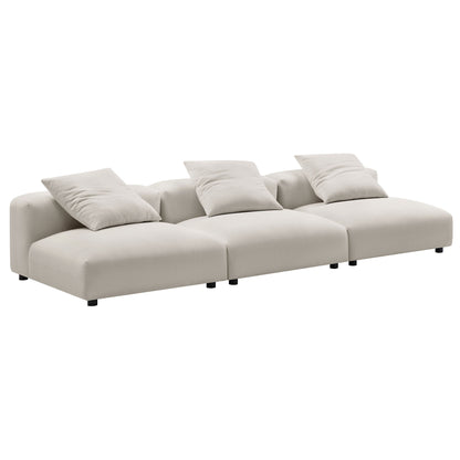Gray modular sectional sofa with three connected seats, plush back cushions, low-profile frame, short black legs.