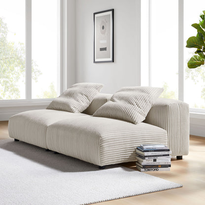 Brown corduroy modular sofa with ribbed upholstery and two pillows in bright living room; books stacked nearby.
