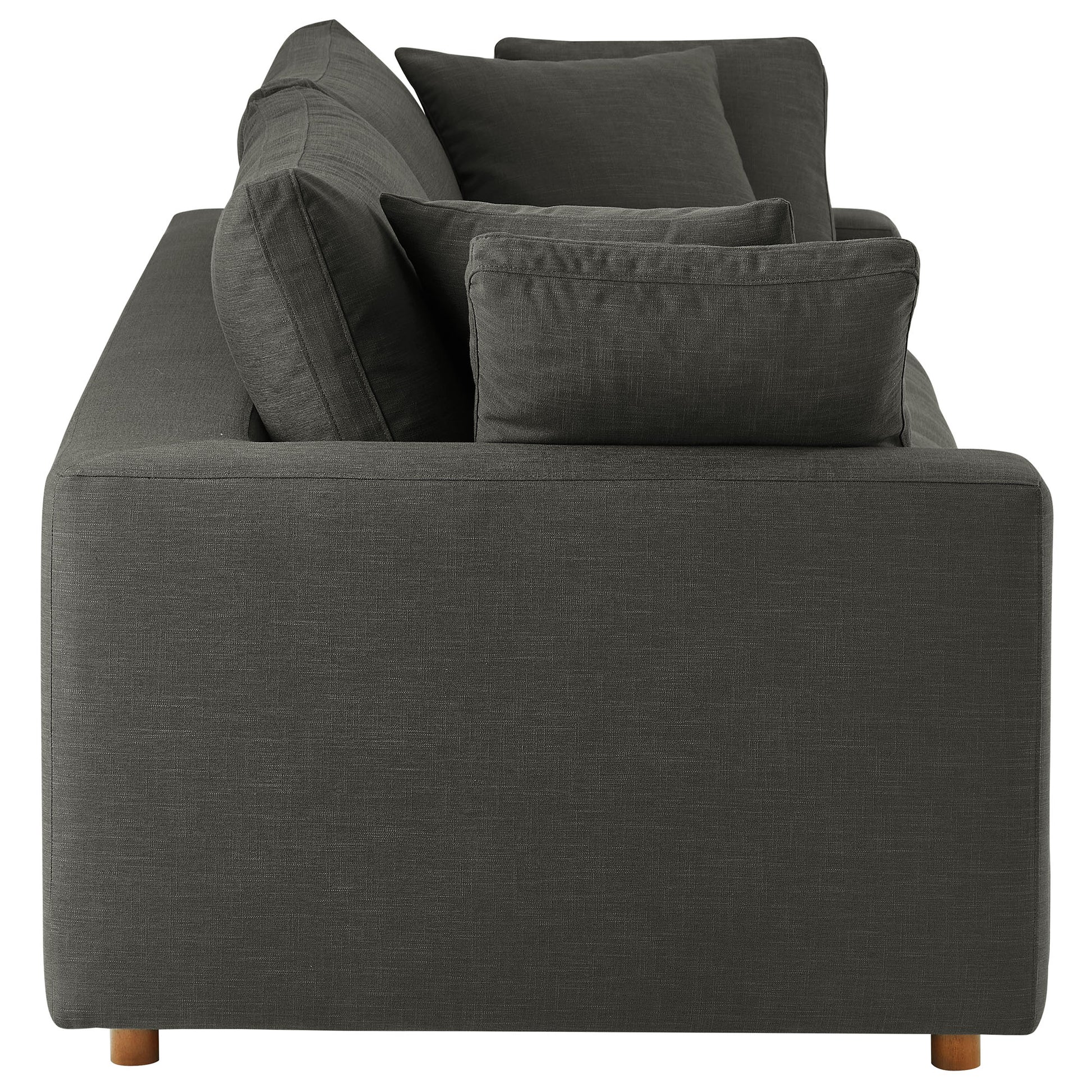 Rear view of a dark gray fabric sofa with square arms and multiple cushions on short wooden legs.