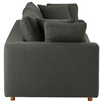 Rear view of a dark gray fabric sofa with square arms and multiple cushions on short wooden legs.