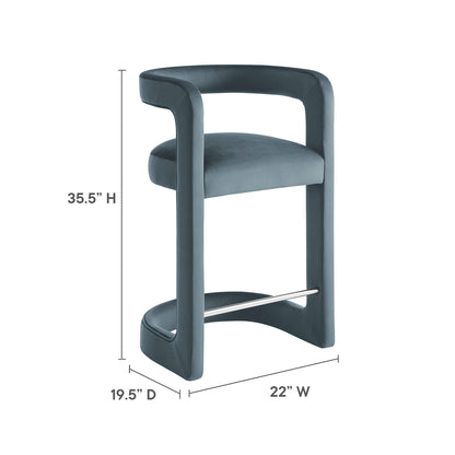 Blue velvet armless counter stool with curved back and metal footrest, 35.5” H x 22” W x 19.5” D.