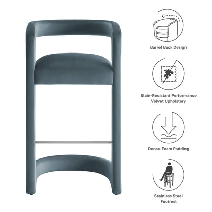 Blue velvet bar stool with barrel-back design, dense foam padding & stainless steel footrest.