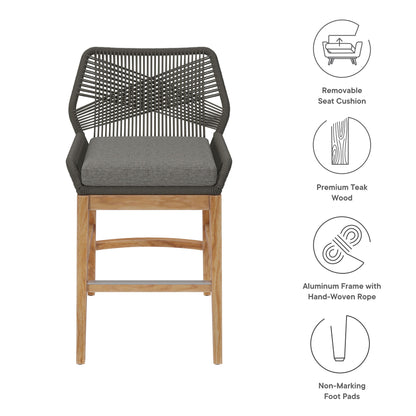 Bar-height outdoor counter stool with gray seat cushion, black hand-woven rope back, teak wood legs and aluminum frame.