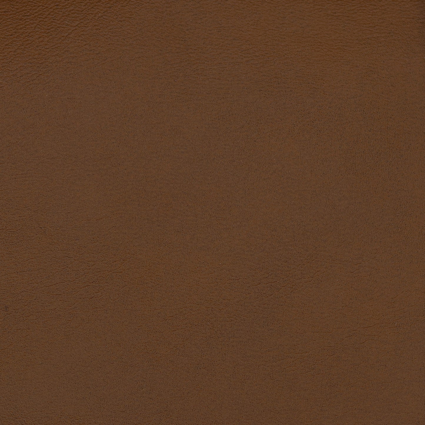 Close-up of brown vegan leather upholstery texture with fine grain & warm chestnut color.