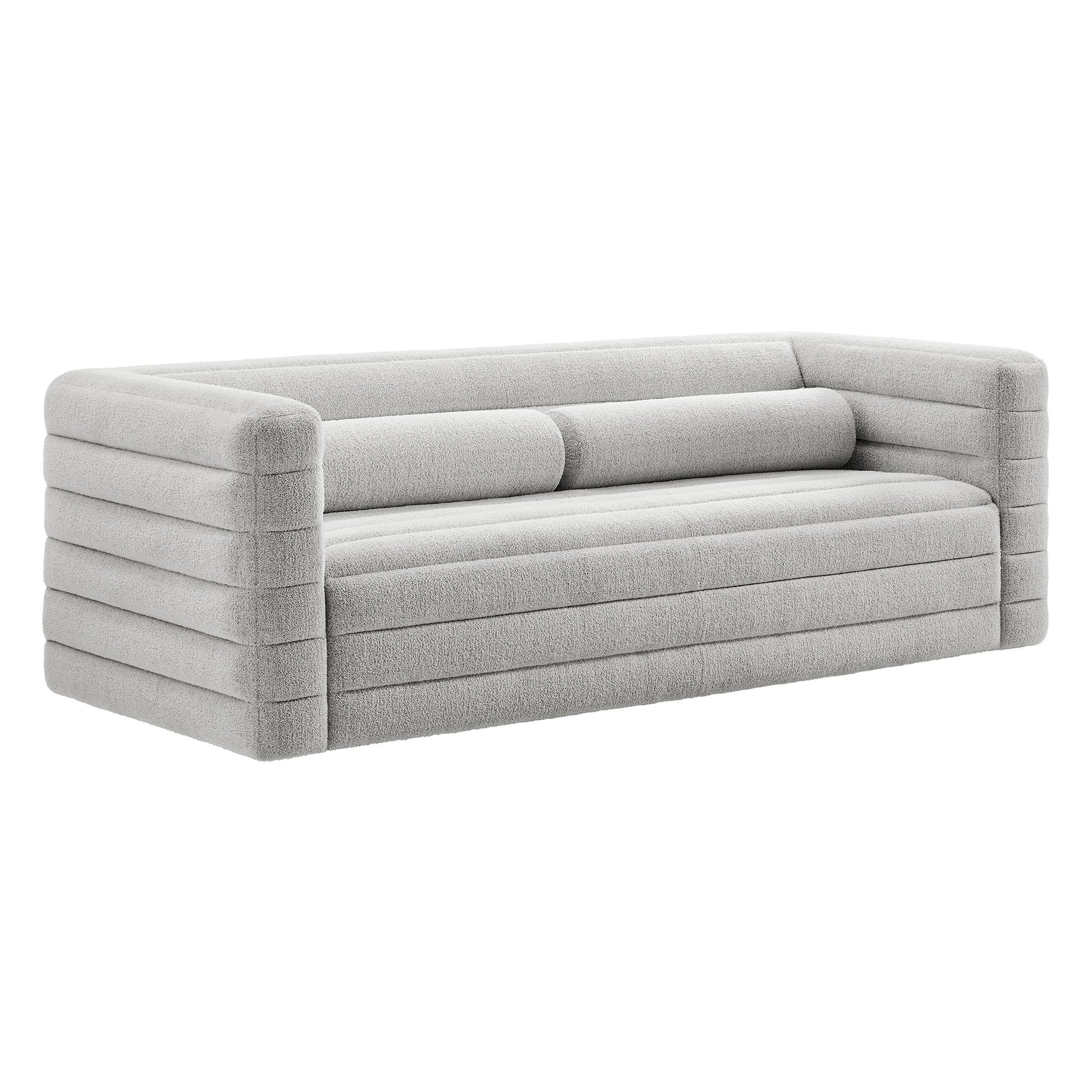 Light gray fabric sofa with rounded block arms, horizontal channel stitching and two cylindrical back cushions.