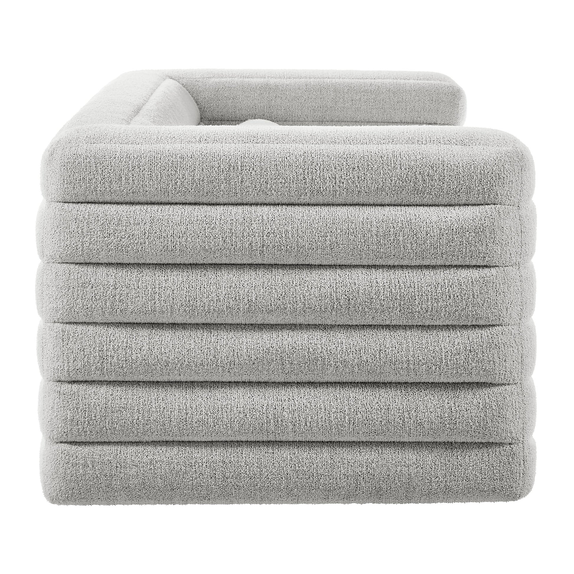 Light gray plush boucle upholstered sofa with channel tufting; modern living room seating.