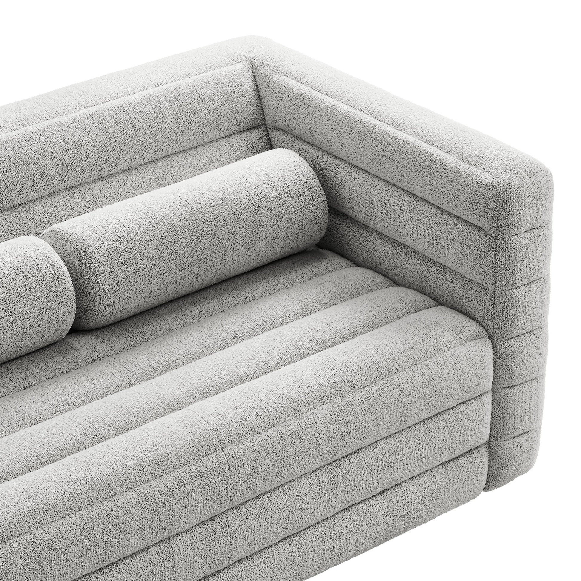 Light gray boucle fabric loveseat with channel-tufted back, ribbed cushions and a cylindrical bolster pillow, modern design.