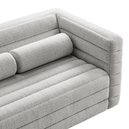 Light gray boucle fabric loveseat with channel-tufted back, ribbed cushions and a cylindrical bolster pillow, modern design.