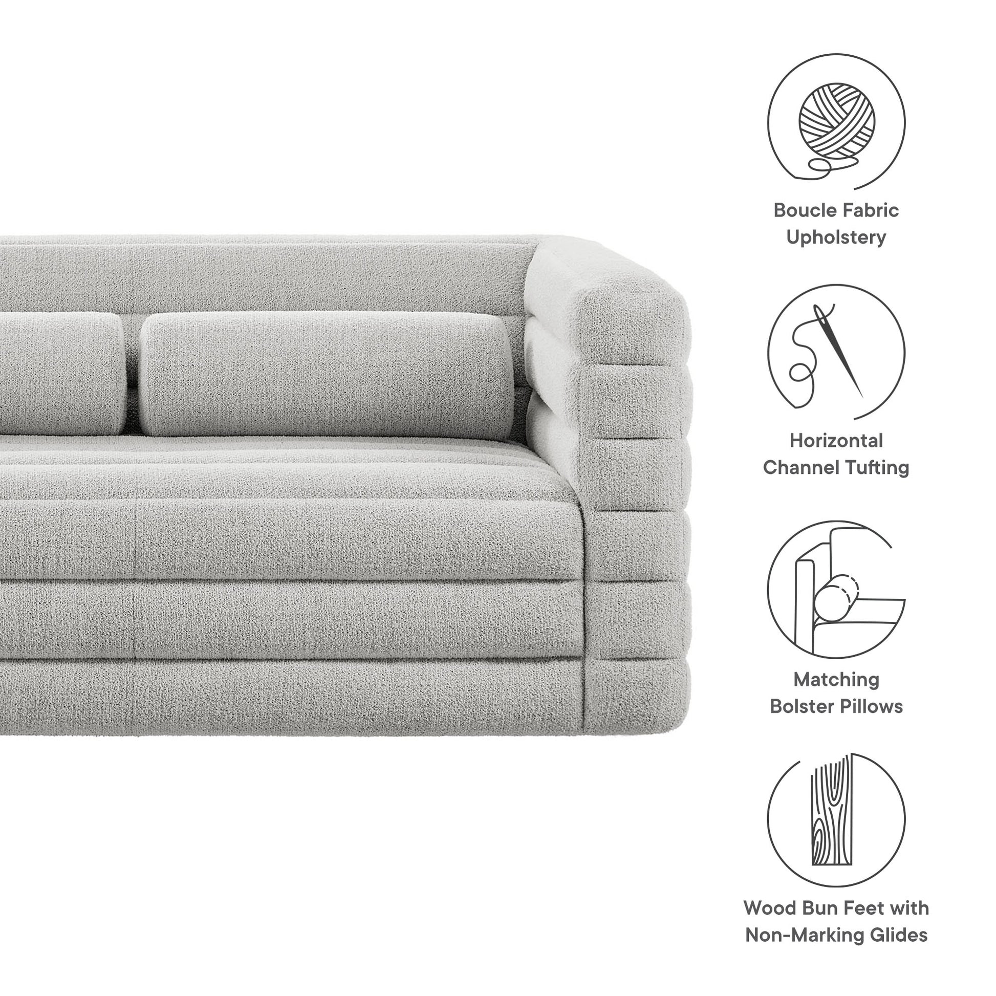 Light gray boucle fabric loveseat with horizontal channel tufting, matching bolster pillows, and wood bun feet.