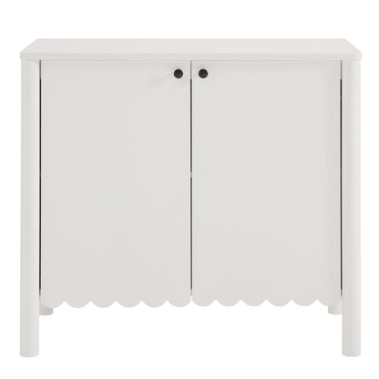 White wooden cabinet with two doors, scalloped bottom edge, and black round knobs for storage.