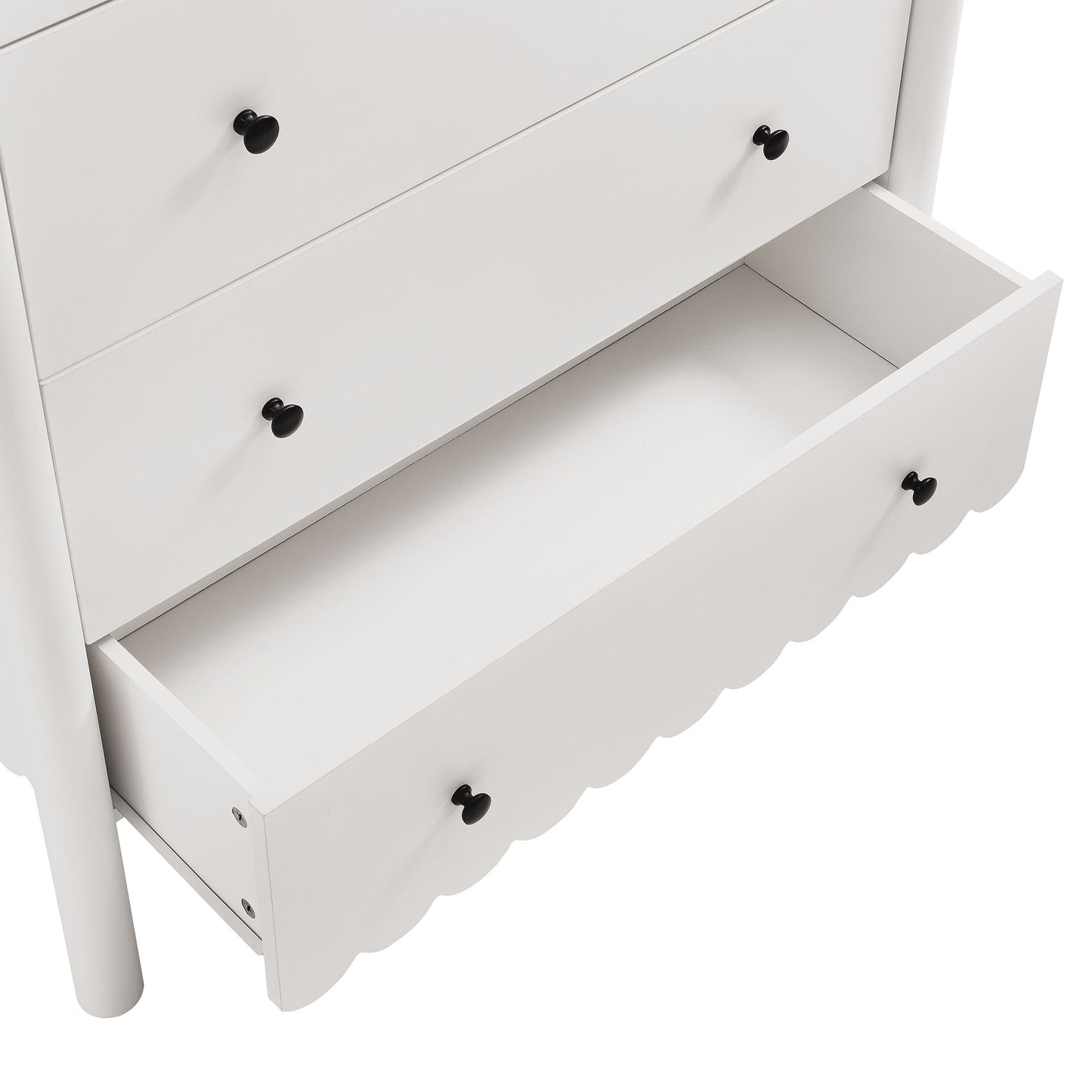 White wooden dresser with black round knobs; scalloped-front bottom drawer pulled open.