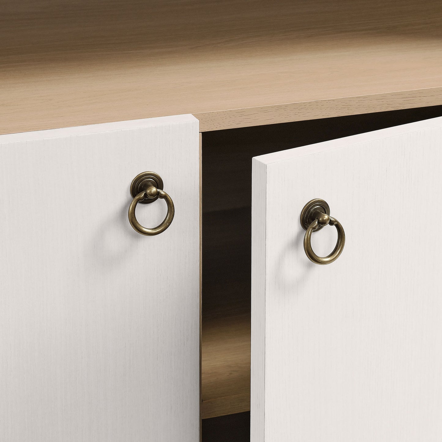 White cabinet doors with brass ring pulls; open to a light oak interior shelf.