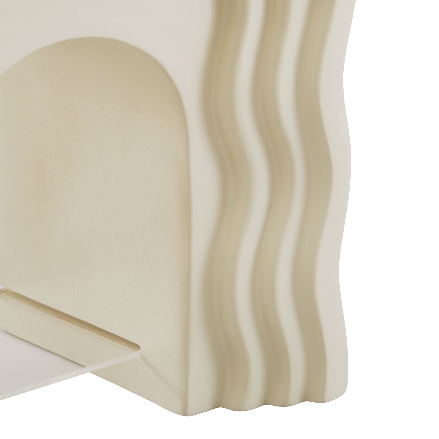 Ivory side table with a rounded arch silhouette and vertical wavy ridges along the edge.